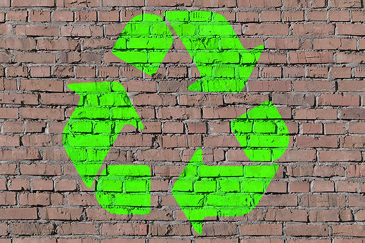 a green recycling symbol on a brick wall